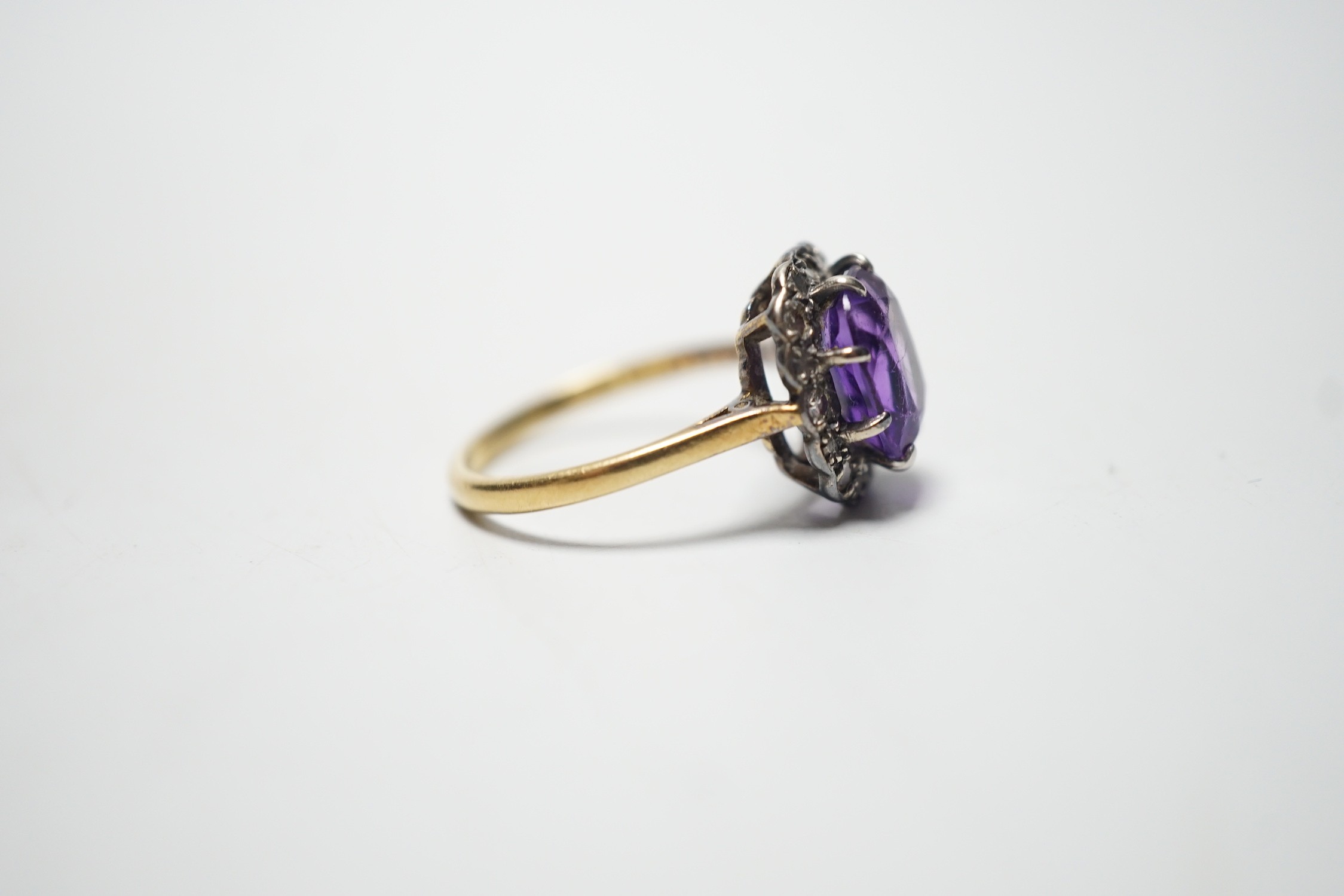 An 18ct, amethyst and diamond set oval cluster ring, size P, gross weight 4.5 grams.